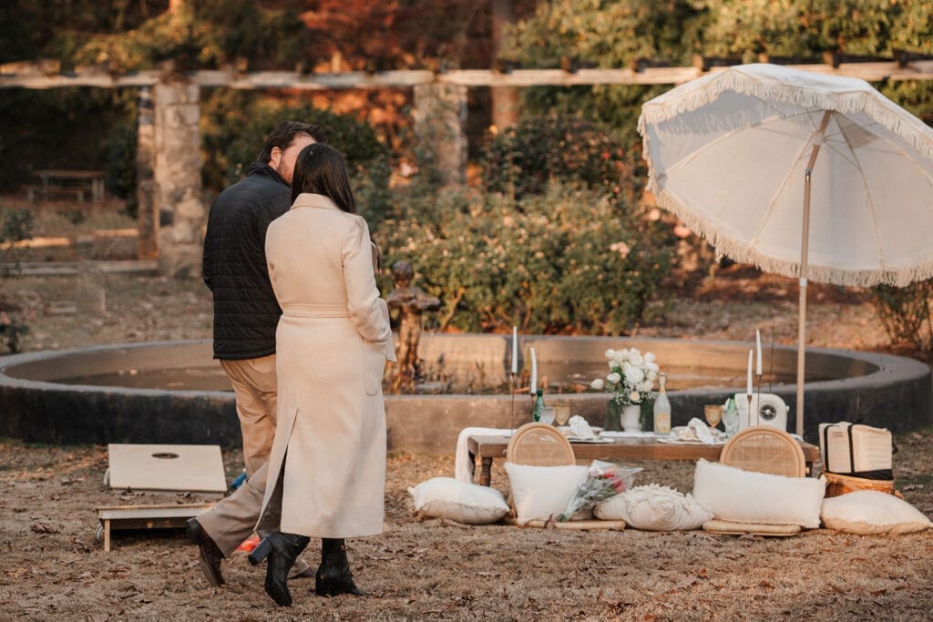Couple walking toward surprise proposal setup at Raleigh Rose Garden in North Carolina.