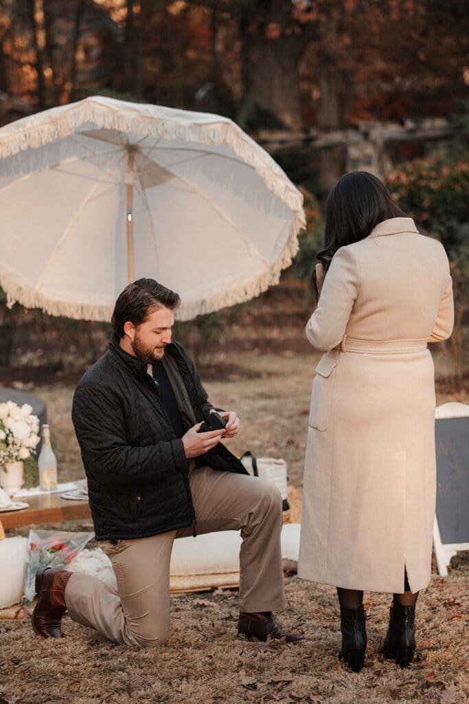 Man kneeling during Raleigh Rose Garden proposal as partner reacts with surprise.
