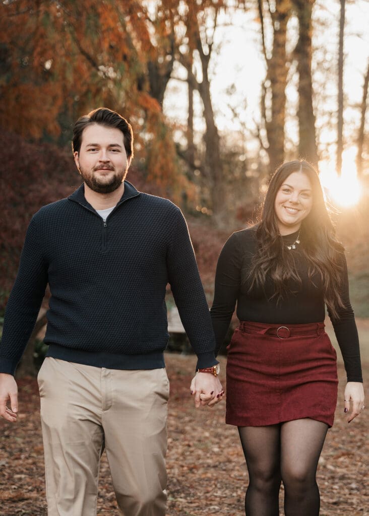 Engaged couple walking hand in hand through Raleigh Rose Garden at golden hour.