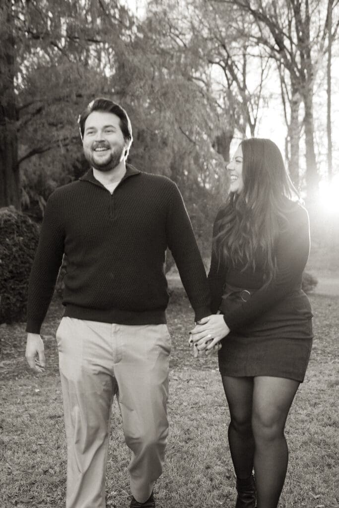 Black and white engagement portrait of couple strolling through Raleigh Rose Garden.