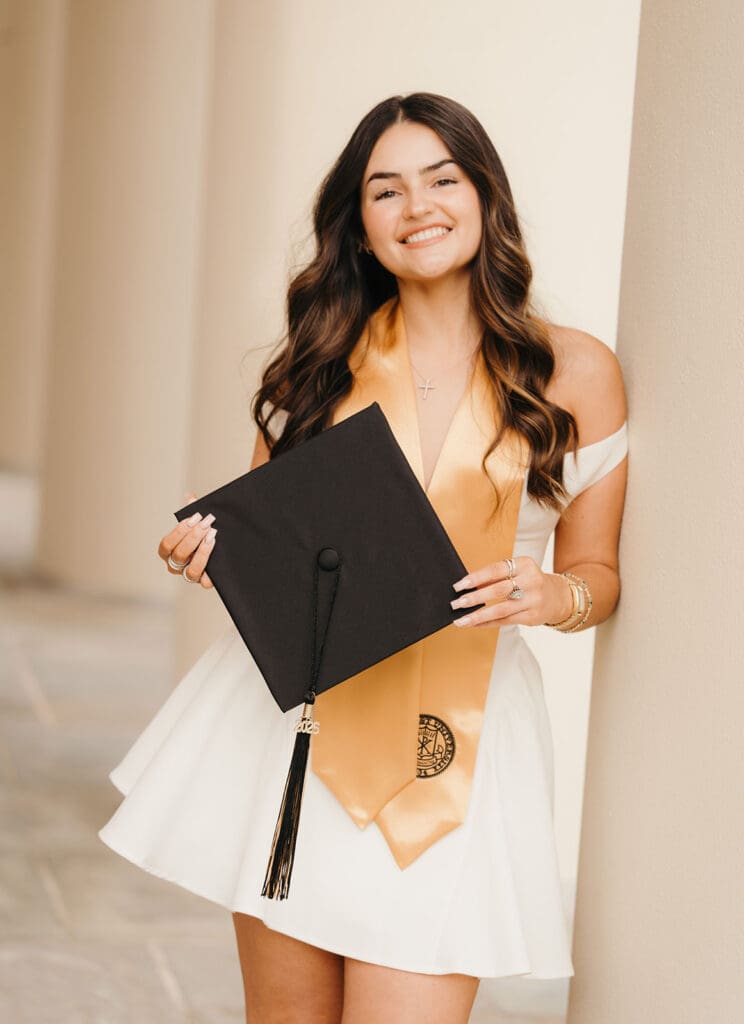 Wake Forest graduate smiling during senior portrait session near campus columns