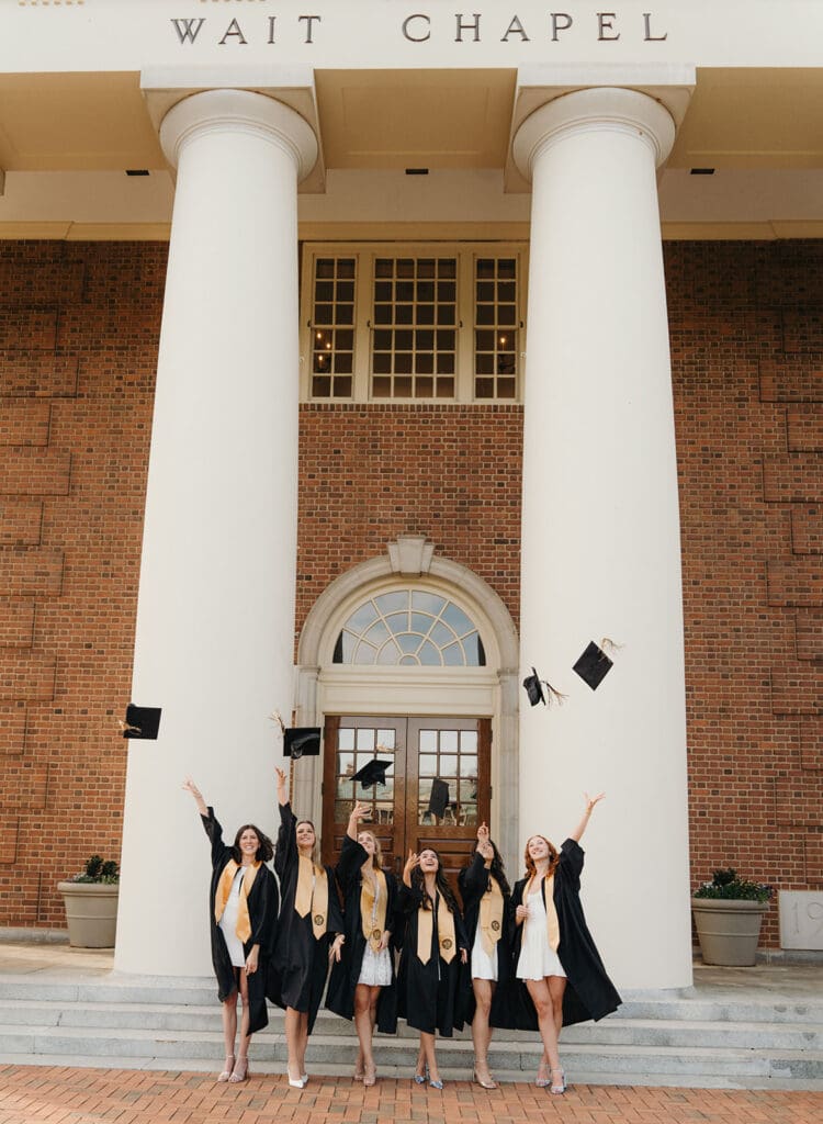 Group of Wake Forest seniors tossing caps in front of Wait Chapel on graduation day