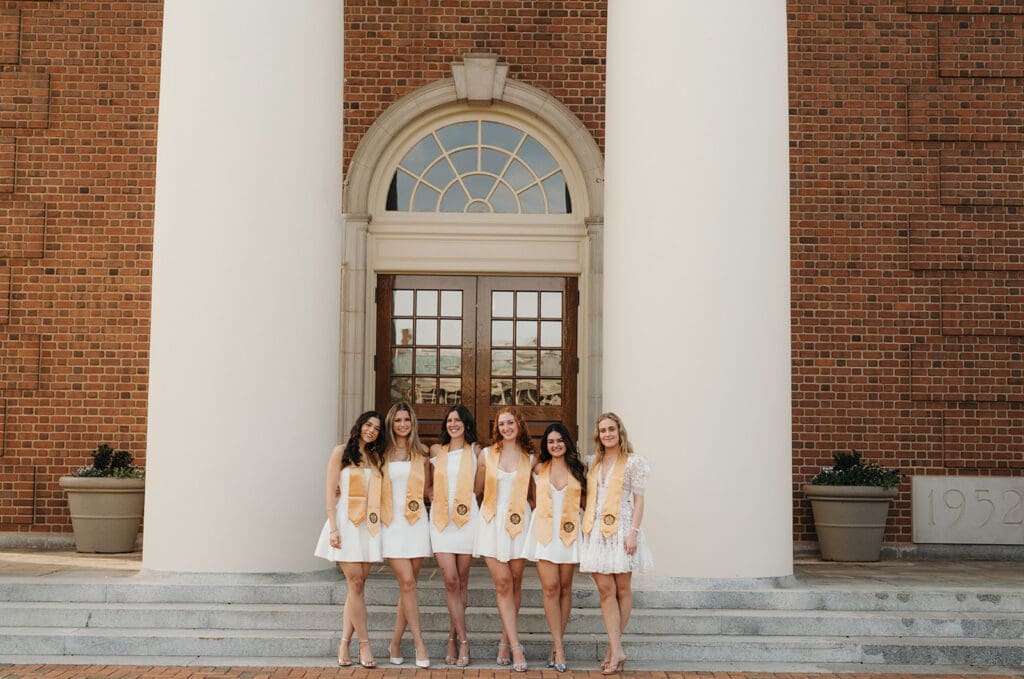 Group of Wake Forest graduates posing together in front of Wait Chapel during graduation photos