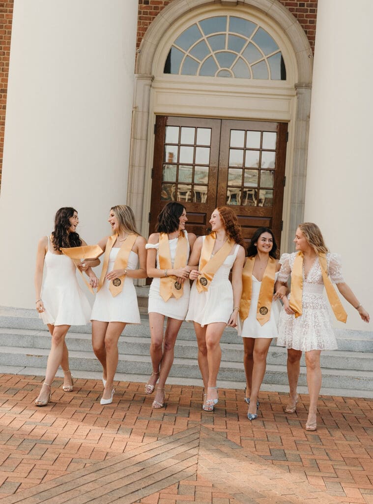 Wake Forest graduates walking together on campus in front of Wait Chapel during senior portraits