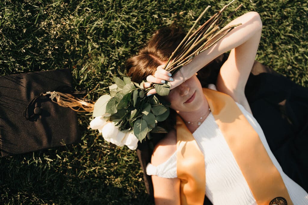 Creative Wake Forest graduation photo featuring diploma and florals during editorial senior portraits