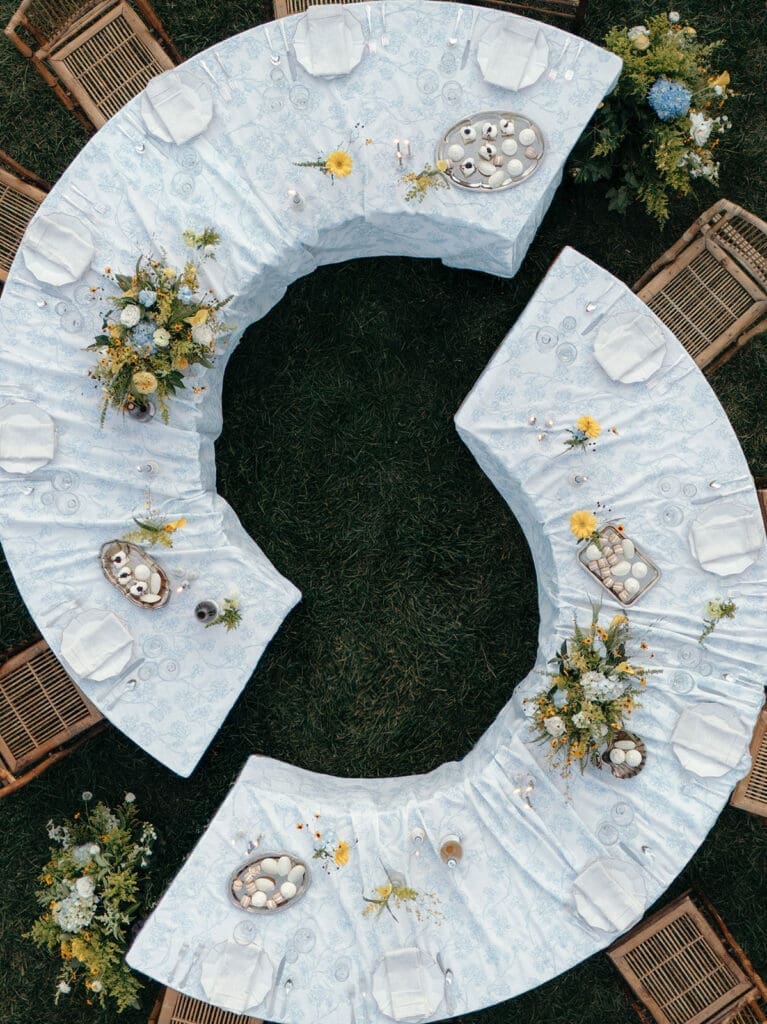 Overhead view of curved reception tables with blue linens and floral arrangements at Le Château du Coeur.