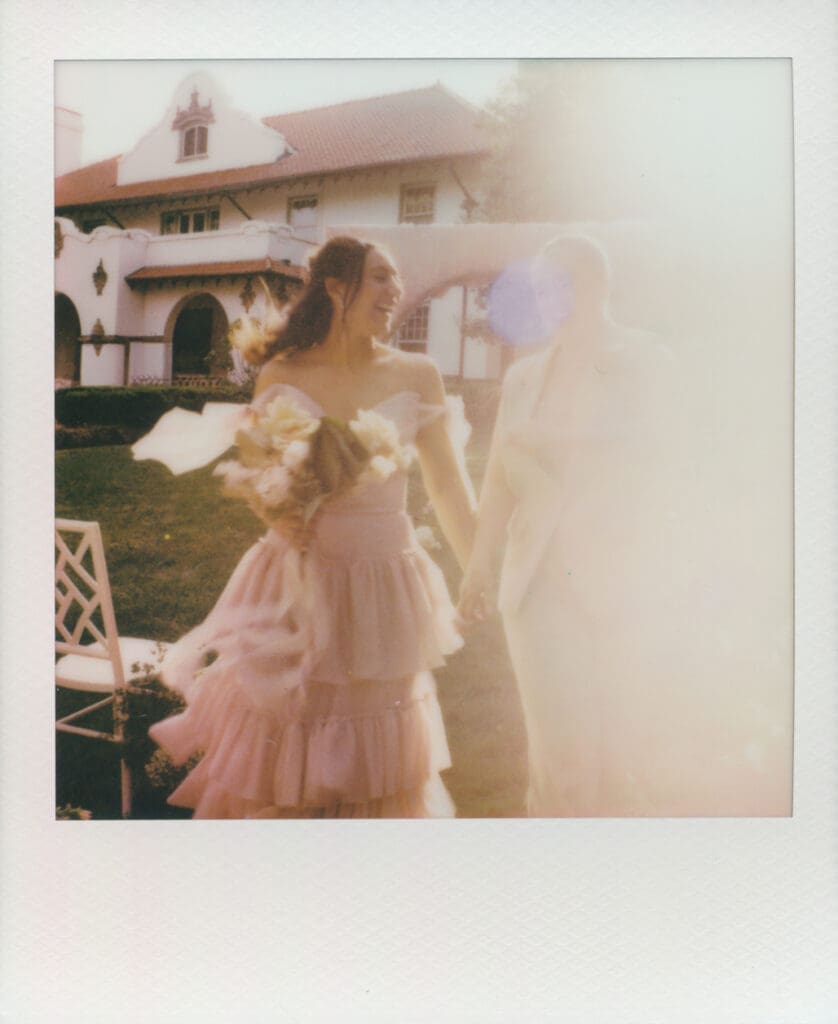 Instant film photo of a couple walking through the gardens at Hill House.