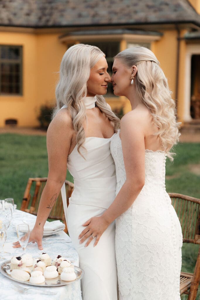 Same-sex couple embracing beside the wedding reception at Le Château du Coeur.