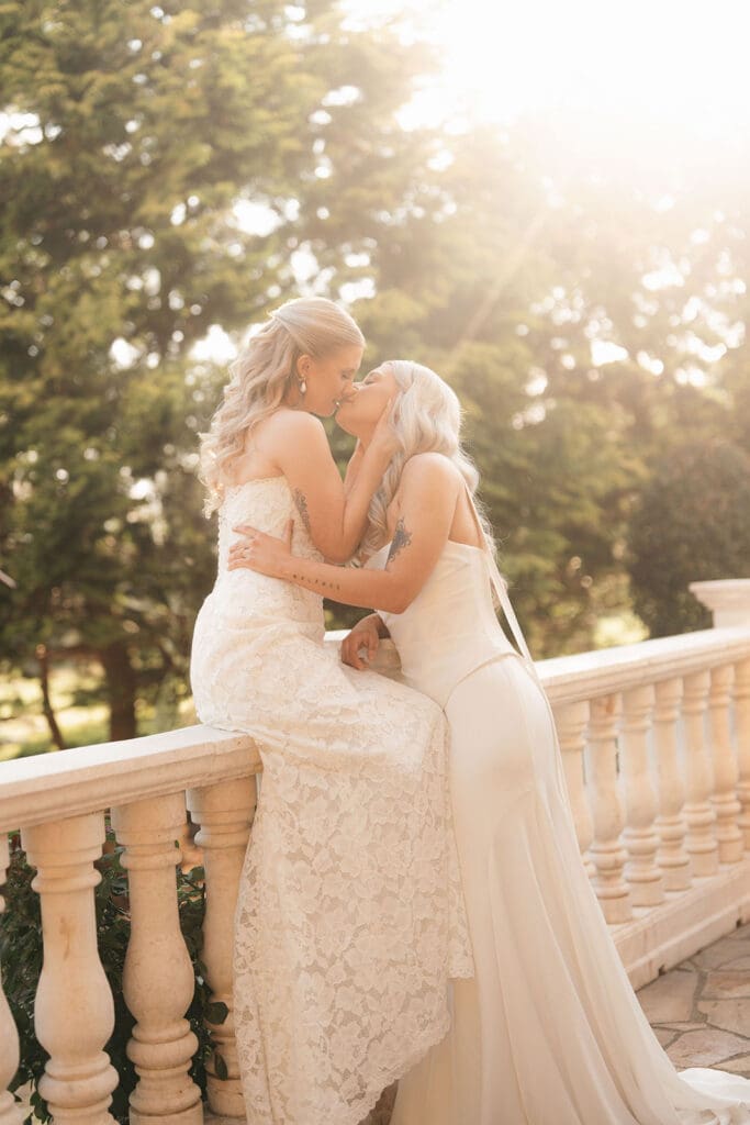 Romantic portrait of two brides kissing on the stone terrace at Le Château du Coeur.
