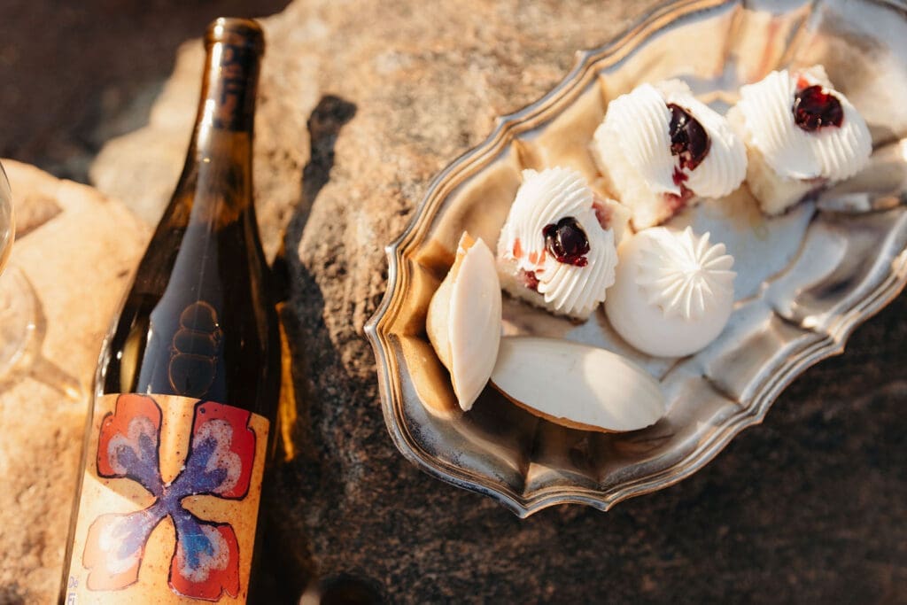 Wine and French pastries displayed on rocks for an editorial wedding reception.