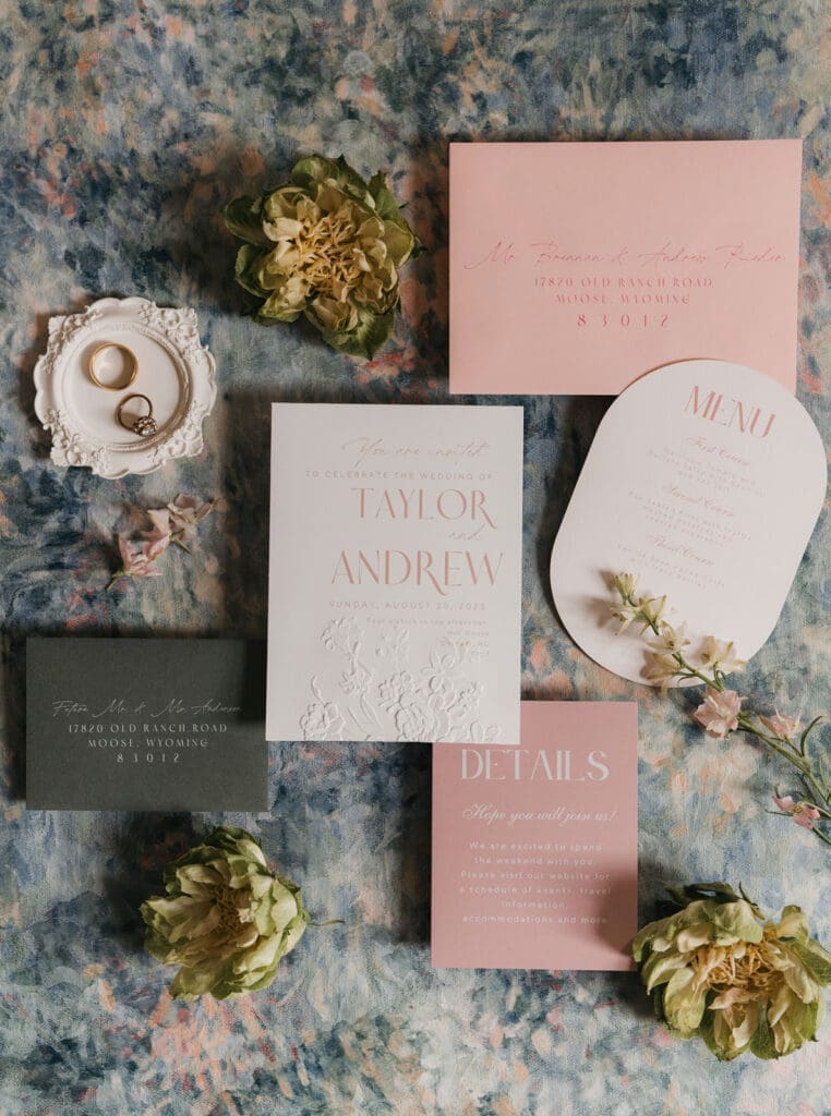 Romantic wedding invitation suite with blush stationery, rings, and floral details.
