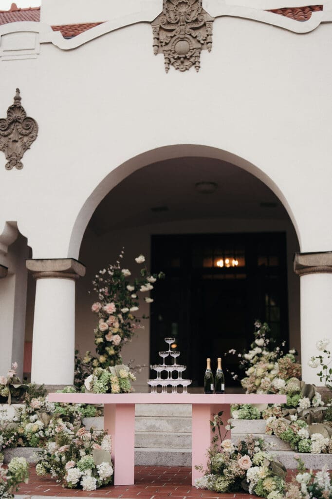 Champagne tower surrounded by floral arrangements for a Hill House wedding reception.